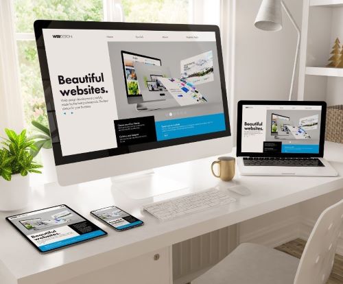 Website design displayed on a desktop monitor, laptop, tablet, and smartphone on a white desk